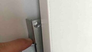 A hand pressing a metallic latch on a white door.