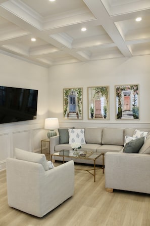 A modern living room with a flat-screen TV, two sofas, a coffee table, and framed artwork on the wall. - The Hawthorn House- Walk to King! (Charleston)