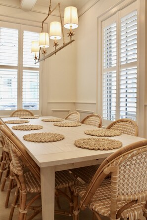 A dining room with a long table, wicker chairs, and a chandelier with star-shaped lamps. - The Hawthorn House- Walk to King! (Charleston)