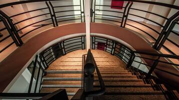 A curved staircase with metal railings and carpeted steps.