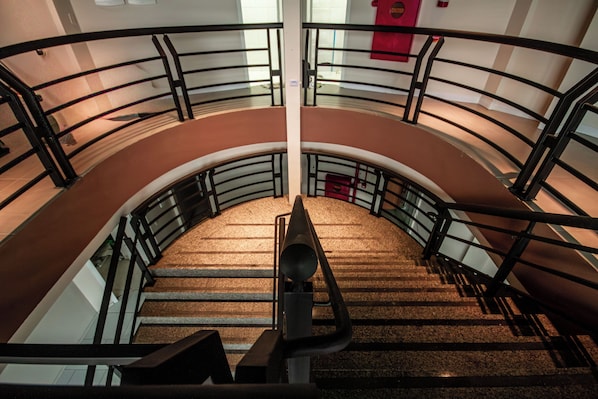 A curved staircase with metal railings and carpeted steps.