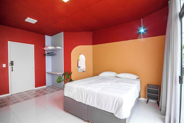 A bedroom with a bed, a wardrobe, a mirror, and a plant.