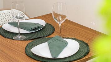 Una mesa de madera para comer con dos platos, cada uno con una servilleta doblada y un vaso.