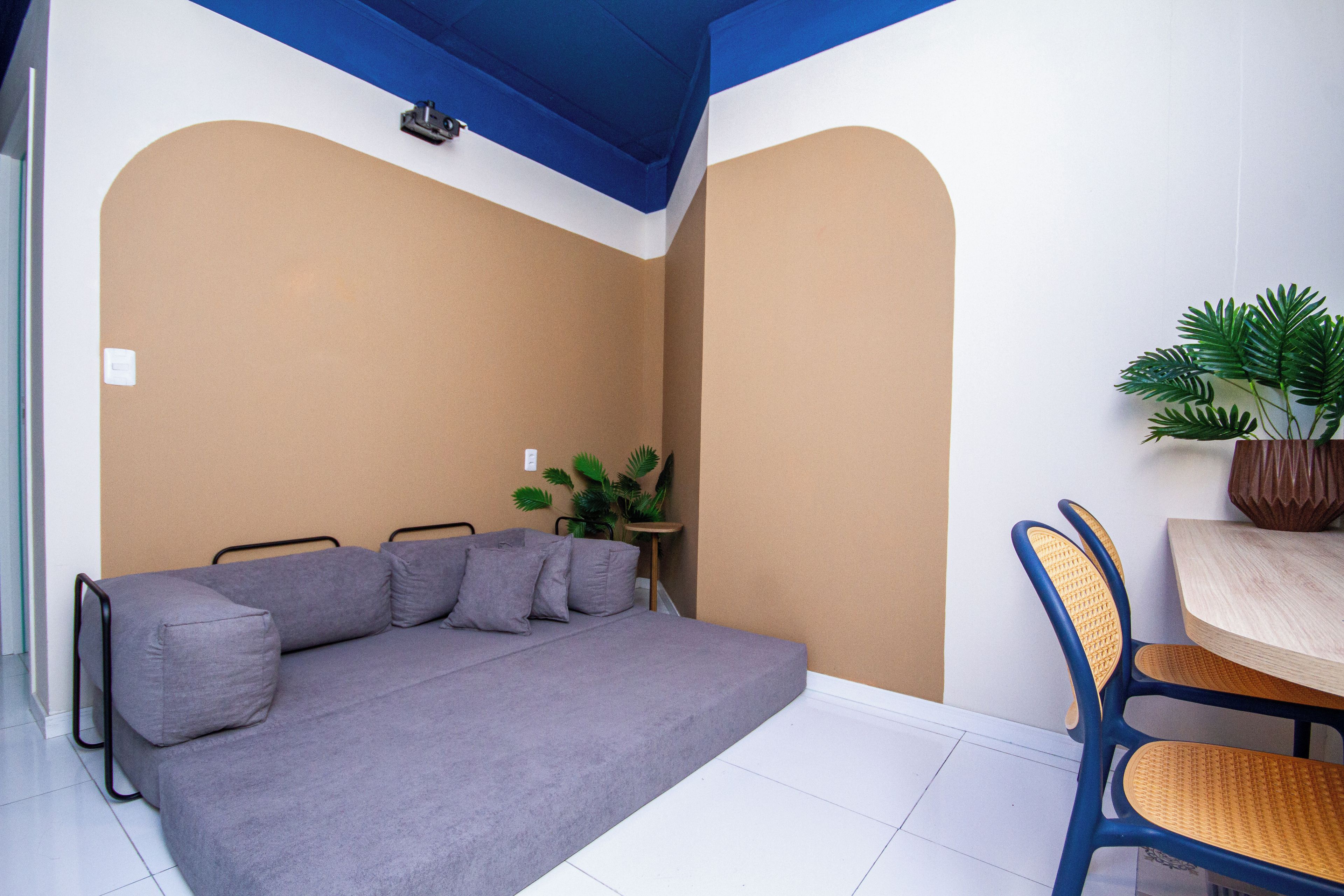 A room with a sofa, a small table, a chair, and a potted plant.
