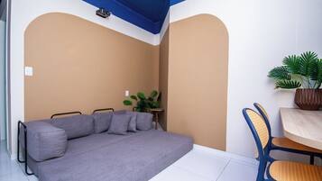 A room with a sofa, a small table, a chair, and a potted plant.