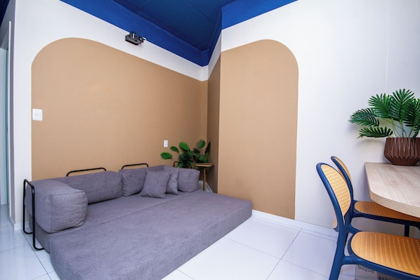 A room with a sofa, a small table, a chair, and a potted plant.