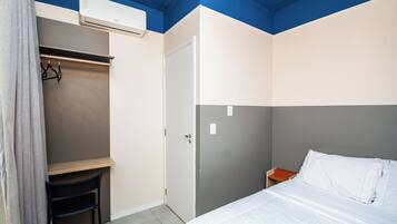 A room with a bed, a wardrobe, a chair, and an air conditioning unit.