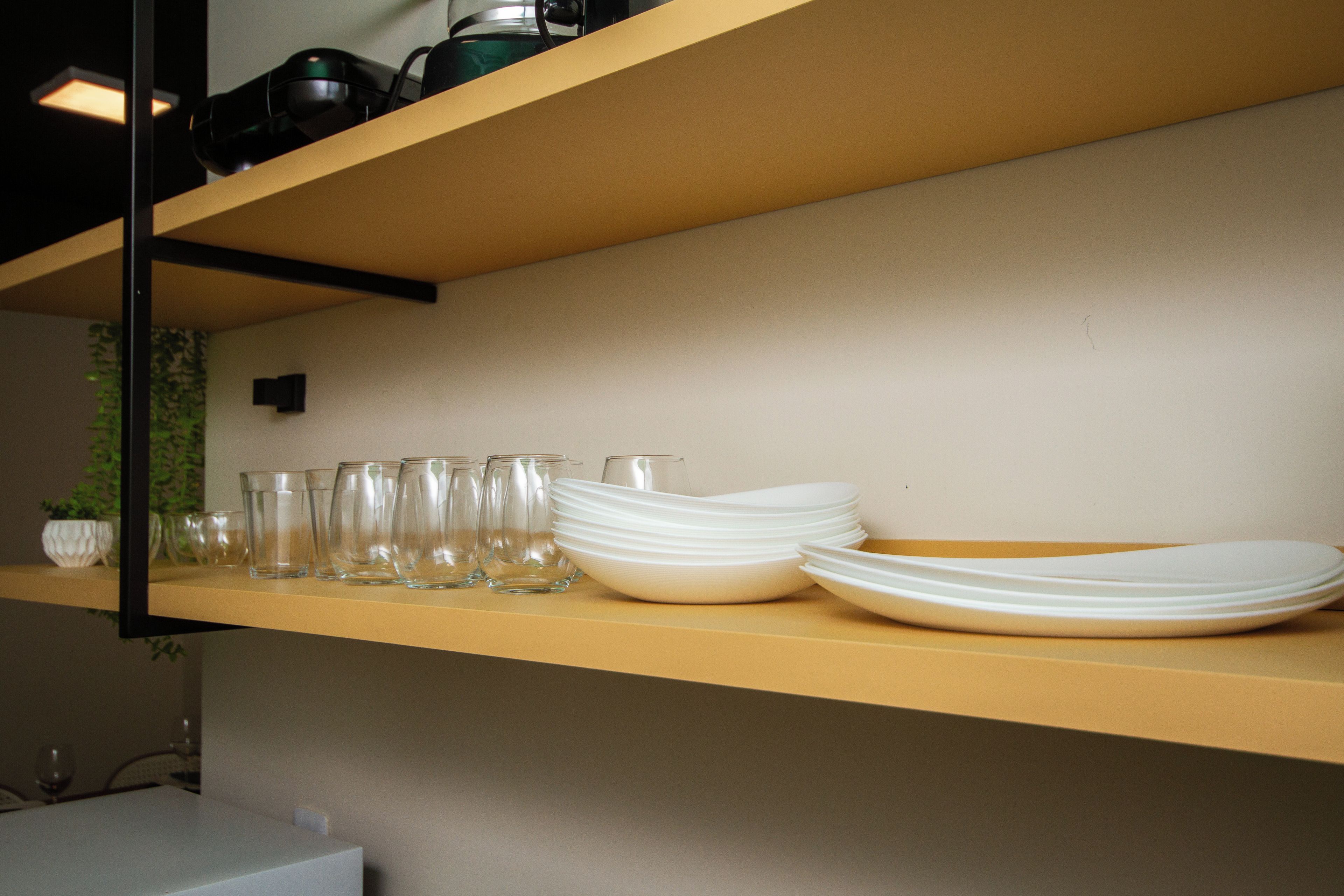 Une étagère de cuisine avec différents types de verrerie et des assiettes blanches.
