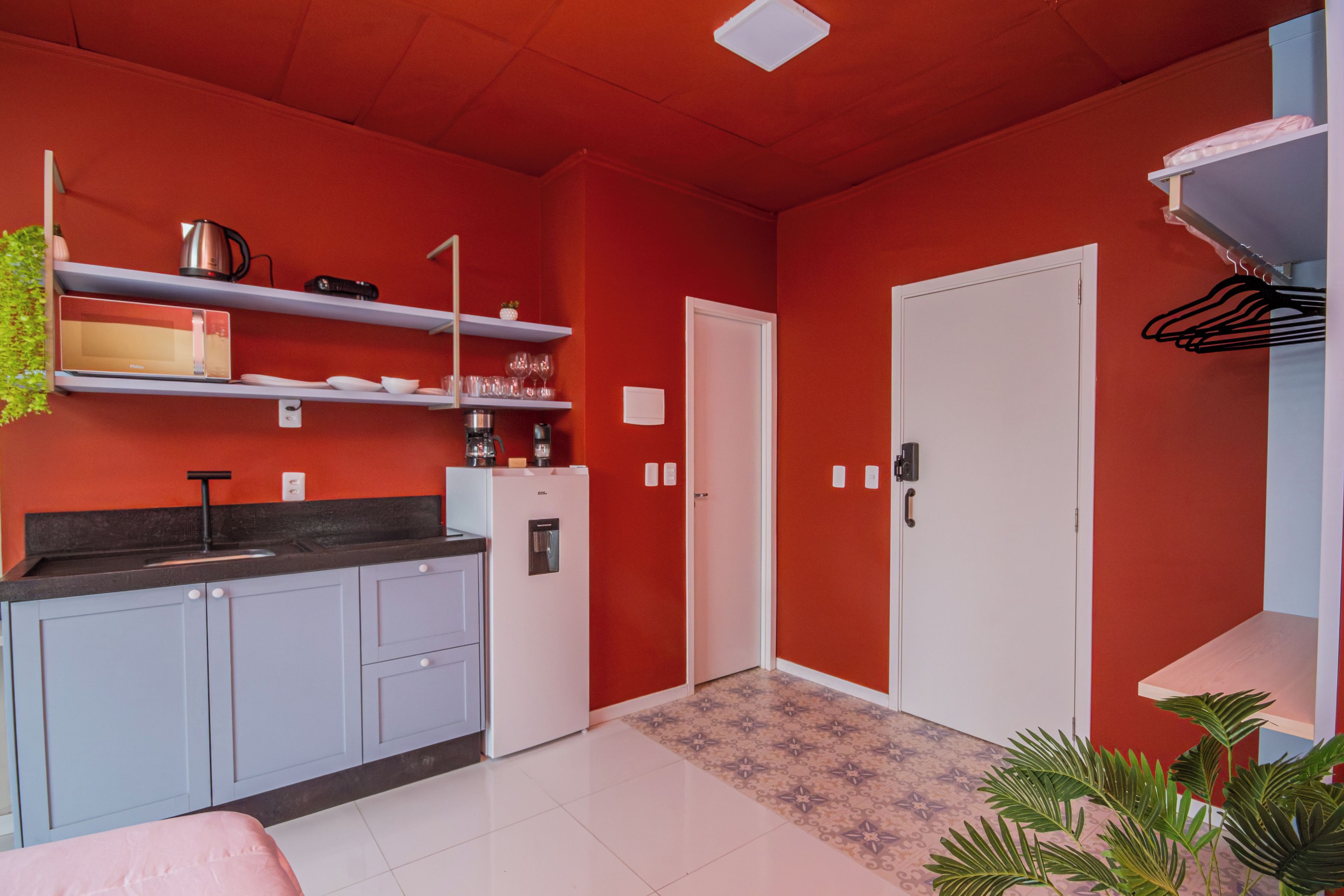 Una cocina compacta con armarios blancos, un refrigerador y una encimera con varios objetos.