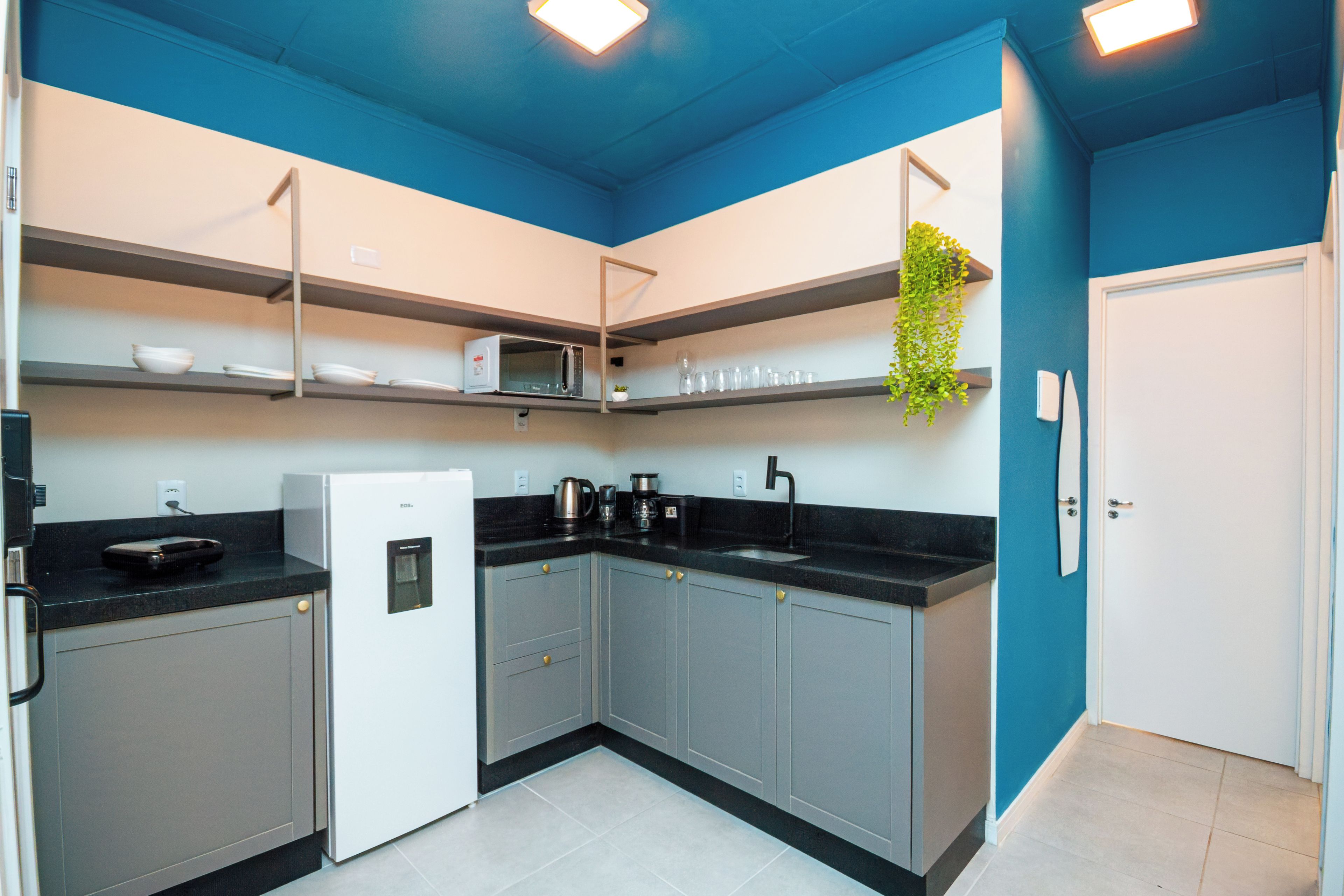 Una cocina moderna con armarios grises, un refrigerador blanco y una encimera negra.