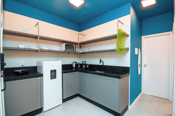 A modern kitchen with grey cabinets, a white refrigerator, and a black countertop.