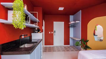 A modern bedroom with a bed, a bathroom, and a kitchenette.