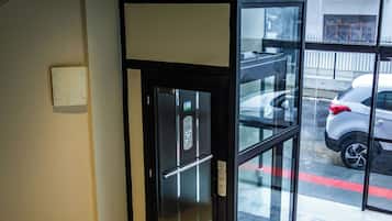 A modern elevator with glass doors, a metal handrail, and a patterned floor.