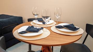 A round dining table with three plates, each with a folded napkin and a glass of water. The table is surrounded by four chairs.