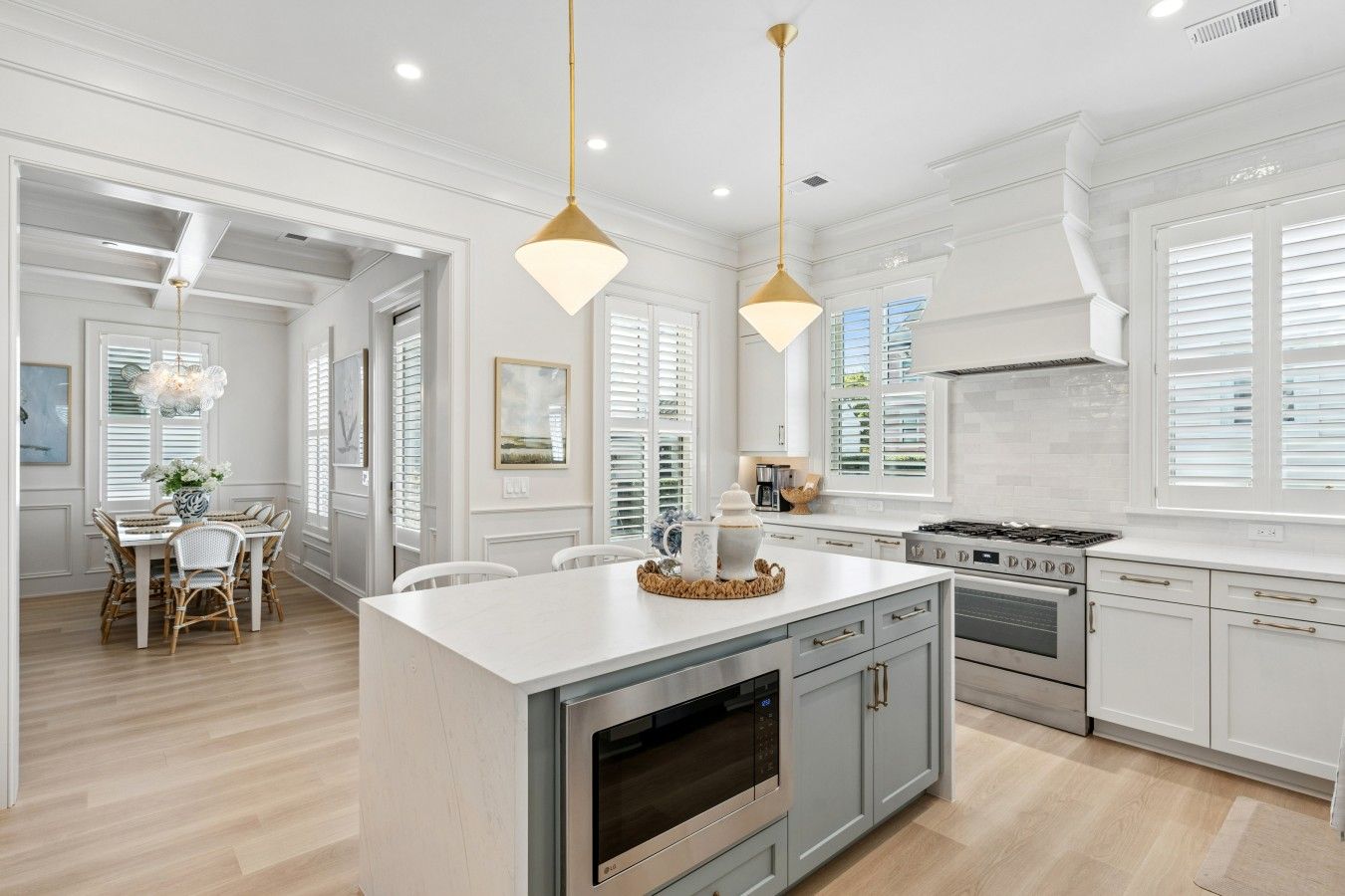 A modern kitchen with white cabinetry, a central island, stainless steel appliances, and pendant lighting.