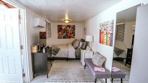 A bedroom with a bed, bedside table, lamp, and artwork on the walls. - RAS Casita Encanto (West Palm Beach)