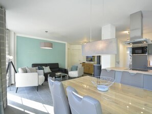 A modern living room with a sofa, a dining table with chairs, and a kitchen area with a stove and microwave. - House North Sea Beach Ground Floor (Wyk auf Foehr)