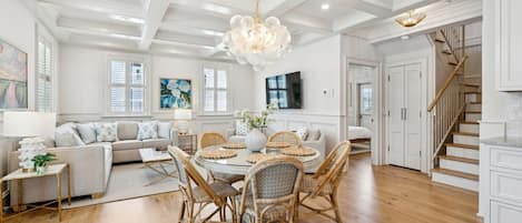 A spacious living room with a dining area, wooden floors, and a staircase.
