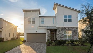A modern two-story house with a garage, a stone facade, and a well-maintained lawn. - This Lakeview Luxury Home & Outdoor Haven (Kissimmee)