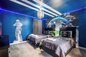 A bedroom with two beds, Star Wars themed decor, a Star Wars poster, and a galaxy-themed ceiling light. - Lakeview Villa w/ Themed Rooms & Pool (Kissimmee)