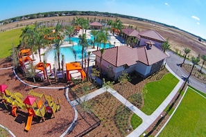A resort with a swimming pool, palm trees, and a playground with slides. - 7BR Near Disney Private Pool, spa & Lake View (Davenport)
