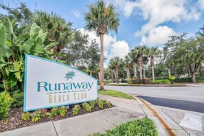 A sign for Runaway Beach Club with a clear sky and palm trees in the background. - 2BR Condo Near Disney Resort Pool (Kissimmee)