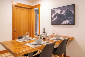 A dining table set for four with wine glasses, a bottle of wine, and a bowl on plates.