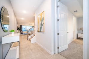 A modern interior with a staircase, a white door, and a large mirror. - Solara Resort 5BR Home with Private Pool (Kissimmee)