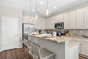 A modern kitchen with white cabinetry, stainless steel appliances, and a granite countertop. - 8BR Near Disney Private Pool, spa & Lake View (Kissimmee)