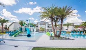 A swimming pool area with a water slide, palm trees, and a building in the background. - 8BR Near Disney Private Pool, spa & Lake View (Kissimmee)