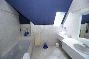 Une salle de bain moderne avec une baignoire, un lavabo, un miroir et une fenêtre.