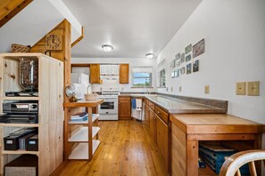 A compact kitchen with wooden cabinetry, a built-in stove, and a wooden dining table. - Cute & Cozy & Remote peace seekers cabin, sleeps 4, 2 bed 2 bath, gorgeous views (Florissant)