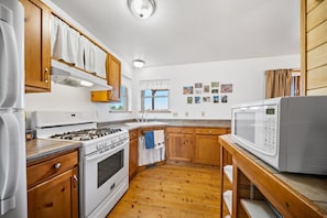A kitchen with wooden cabinets, a stove, a microwave, and a sink. - Cute & Cozy & Remote peace seekers cabin, sleeps 4, 2 bed 2 bath, gorgeous views (Florissant)
