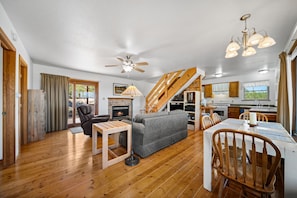 A cozy living area with a fireplace, a sofa, a dining table with chairs, and a kitchen in the background. - Cute & Cozy & Remote peace seekers cabin, sleeps 4, 2 bed 2 bath, gorgeous views (Florissant)
