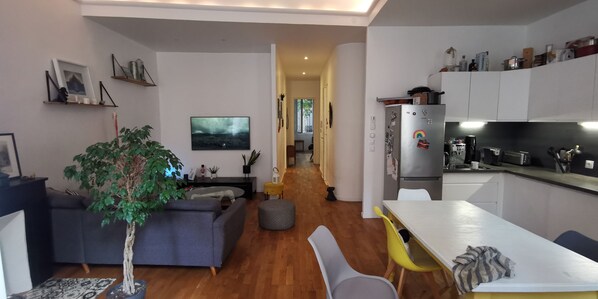Eine moderne Küche mit weißen Schränken, einem Kühlschrank und einem Essbereich mit Tisch und Stühlen.