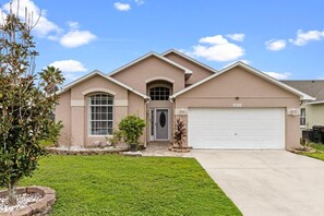 Une maison de plain-pied avec un garage, une porte d’entrée et une pelouse bien entretenue.