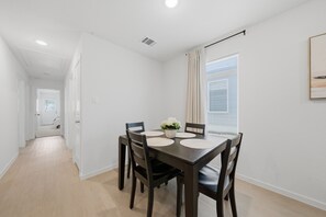 Un comedor con una mesa de madera oscura, cuatro sillas y un jarrón con flores.