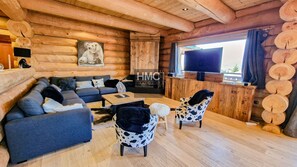 A log cabin interior with a sofa set, two patterned chairs, a coffee table, a TV, and a wooden reception desk. - Nanook, luxe montagnard, sauna et jacuzzi (Bolquère)