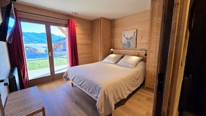 A wooden room with a bed, a window with curtains, and a view of mountains. - Chalet "Luna", superbe vue (Bolquère)