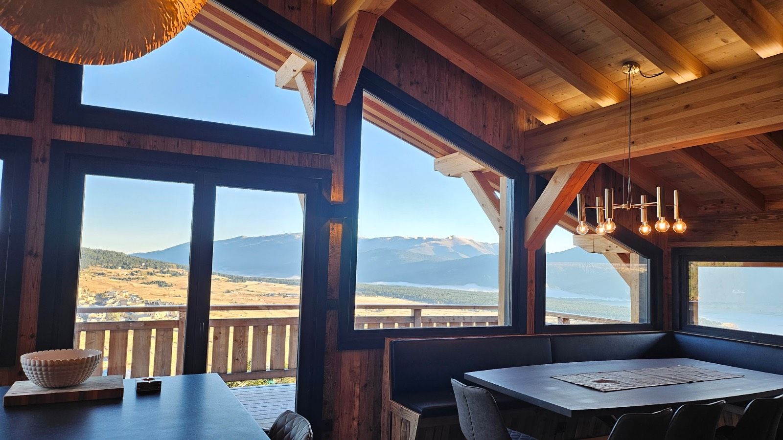 A wooden interior with large windows offering a mountain view.