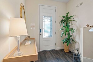 A hallway with a white door, a lamp, a small table with a decorative item, a potted plant, and a metal ladder. - 5BR Near Disney Pool, spa & Game Room (Kissimmee)