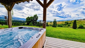 A hot tub on a wooden deck with a scenic view of a green landscape and mountains in the background. - Sjodammen, Jacuzzi & vue époustouflante (Bolquère)