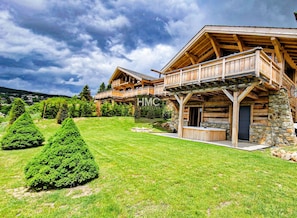 A log cabin with a stone foundation, wooden balconies, and a well-maintained lawn. - Sjodammen, Jacuzzi & vue époustouflante (Bolquère)