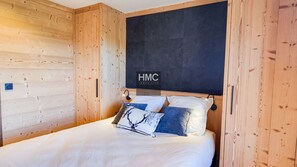 A bedroom with a bed, wooden walls, and a sign reading 'HMC IMMO'. - Sjodammen, Jacuzzi & vue époustouflante (Bolquère)