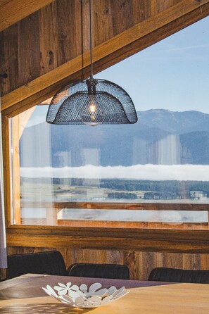 A dining area with a table, chairs, and a hanging light fixture. - Chalet "Nest Lodges" (Les Angles)