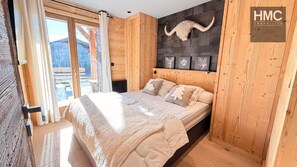 A wooden bedroom with a bed, a headboard with animal horns, and a window with curtains. - Chalet Tichlo, cocooning, jaccuzi (Bolquère)