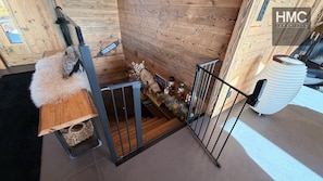 A wooden interior with a staircase, a fluffy white rug, and a small table with a decorative item. - Chalet Tichlo, cocooning, jaccuzi (Bolquère)