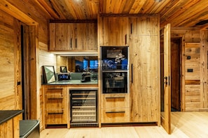 Ein Holzinnenraum mit einer Küchenzeile, inklusive Kühlschrank, Backofen und Tischgeräten.