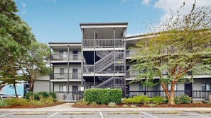 Un immeuble à plusieurs étages doté de balcons, d’un escalier central et d’un parking situé à l’avant.