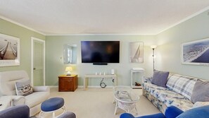 A living room with a television, sofa, armchair, and a small table with a lamp. - Coastal Comfort in the Heart of Midtown Ocean City (Ocean City)